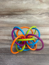 Colorful plastic baby teething toy with interlocking loops on wooden surface