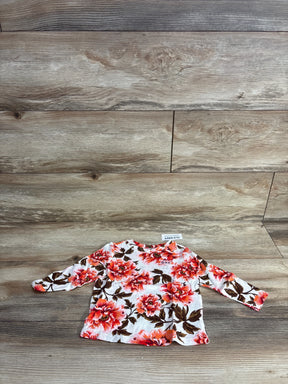 Floral long sleeve baby shirt with red and pink flowers on wooden background