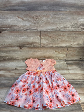 Girls' floral dress with pink lace cardigan and bow, laid on wood floor