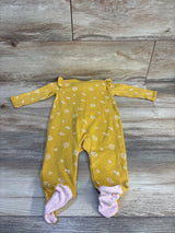 Mustard yellow baby onesie with white daisy print and pink polka dot footies, laid on wood floor