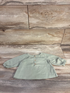 Front view of Carter's long-sleeve henley baby shirt, green 3M, showing button placket and raglan sleeves on wood background