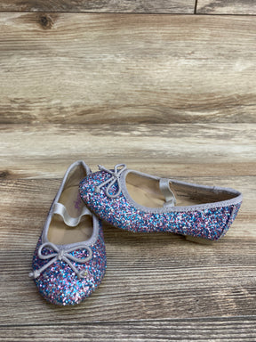 Pair of glittery multicolor girls ballet flats with gray trim and bow on wooden floor