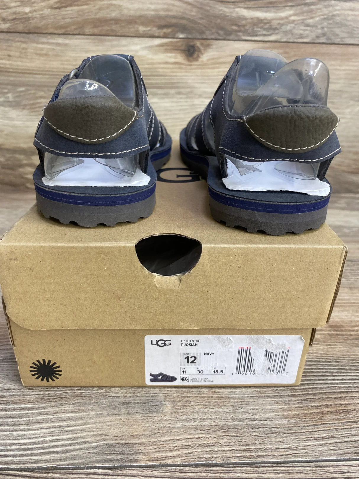 Rear view of UGG Josiah toddler fisherman sandals in navy showing stitched straps and lug sole on shoebox
