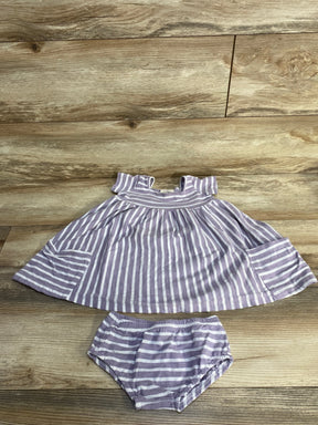 Flat lay of purple and white striped baby dress with matching bloomers, ruffle sleeves and gathered skirt on wood