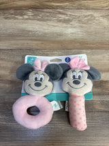 Front view of Disney Minnie Mouse two-piece plush rattles showing a pink ring rattle and a pink polka-dot stick on wood background