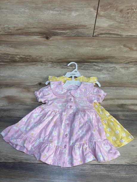 Two toddler girls' floral dresses, pink and yellow, short sleeve, displayed on wooden background