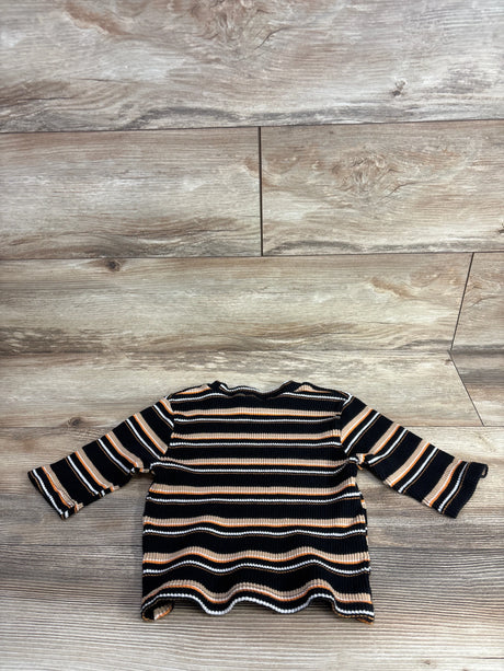Children's long sleeve ribbed shirt with black, brown, and white stripes on wood background