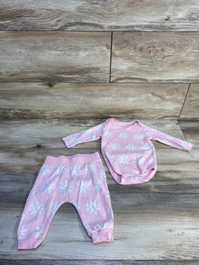 Flat lay of pink baby two-piece with long-sleeve daisy-print bodysuit and cuffed pants on wood floor