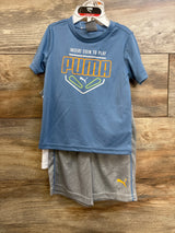 Front view of 3-piece Puma set: blue tee showing INSERT COIN TO PLAY, white tank, gray shorts with yellow Puma logo on wood