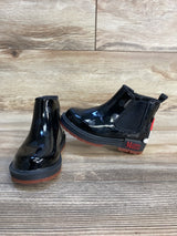 Black Minnie Mouse kids rain boots with polka dots and red soles on wood floor