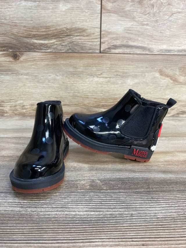 Black Minnie Mouse kids rain boots with polka dots and red soles on wood floor