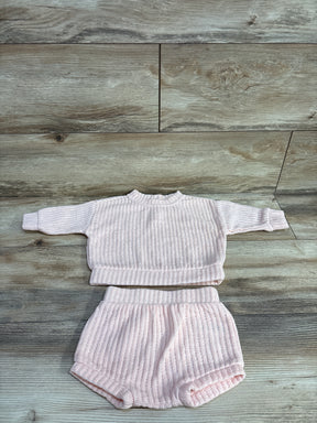 Light pink ribbed baby sweater and shorts set on wood background