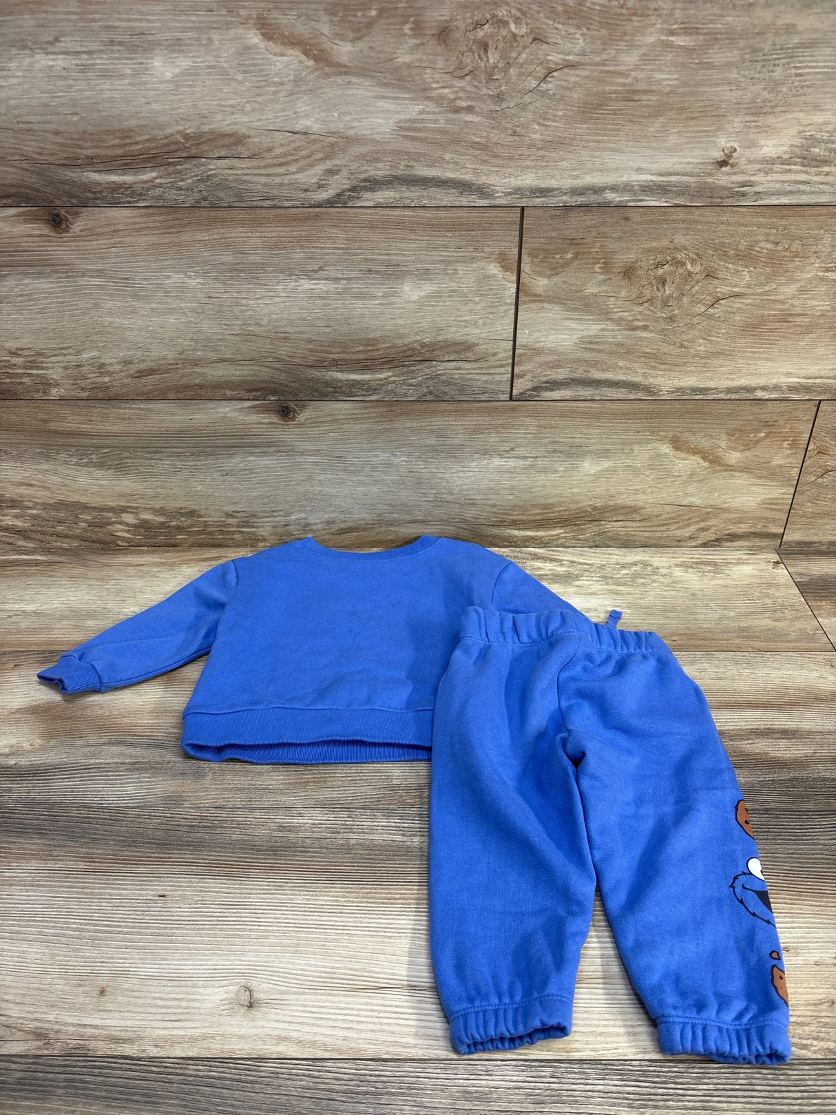Flat lay Baby Gap Sesame Street blue sweatshirt and joggers, back of top visible, Cookie Monster on right pant leg