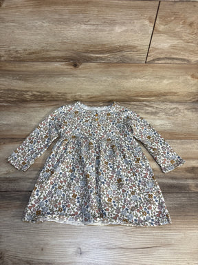 Long-sleeve floral baby dress with multicolor flower pattern on wood background