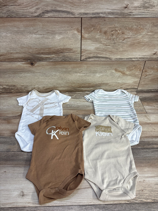 Four Calvin Klein branded baby bodysuits in white, brown, beige, and striped laid on wood floor