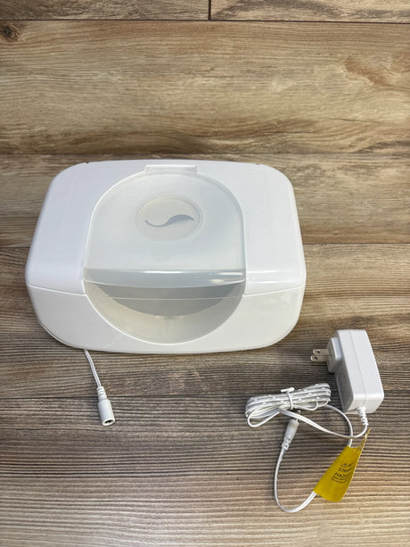 White baby wipe warmer with power adapter on wood floor, ideal for nursery essentials and baby gear