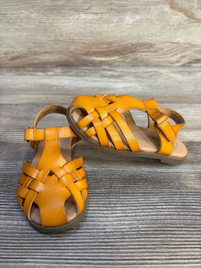 Angled view of Cat and Jack Ella toddler ankle-strap sandal in cognac leather with woven straps and hook-and-loop closure on wood background
