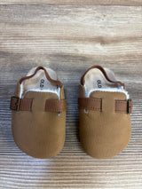 Brown faux leather baby moccasins with buckle detail on wood background