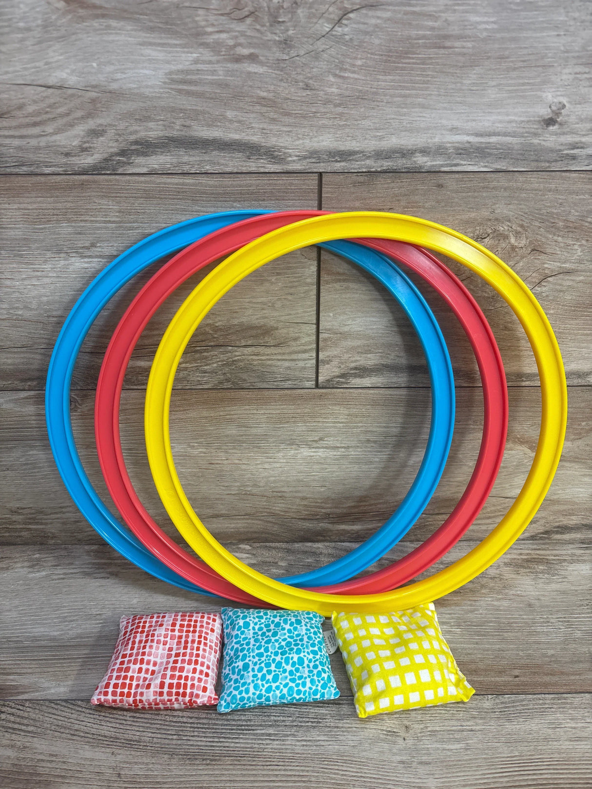 Colorful kids ring toss game with patterned bean bags on wood floor