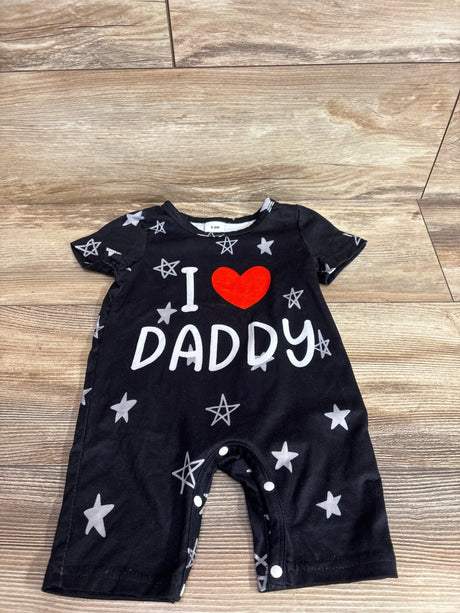 Flat lay of black shortie baby romper (6–9M) with red heart and white 'I DADDY' print, gray stars and crotch snap closures on wood floor