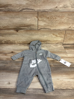Top-down view of grey Nike hooded baby coverall (3M) showcasing front zipper and white Nike logo on wood floor background