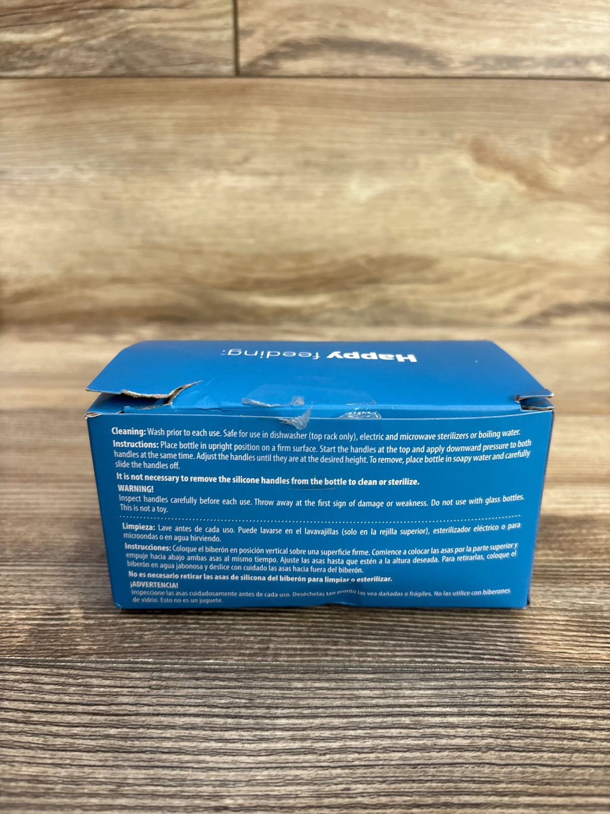Rear of Dr. Brown's silicone narrow bottle handle 3-pack box with care instructions visible and torn top flap on wood surface