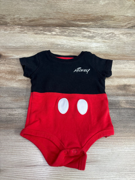 Front view of Disney Store Mickey Mouse bodysuit with black top, red bottom, white oval accents, and snap closures on a wood surface