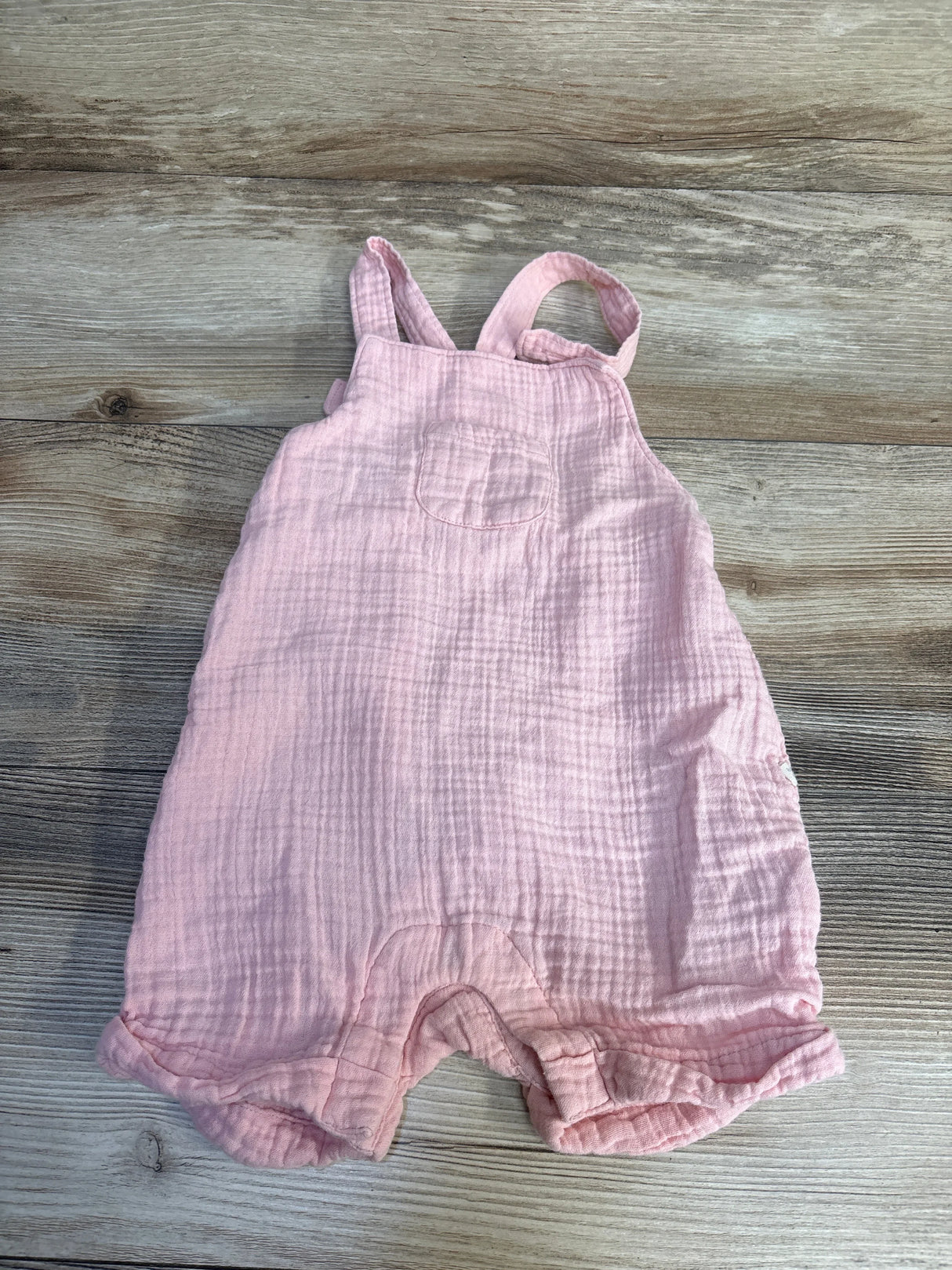 Soft pink muslin baby romper with ruffled legs, perfect for newborns and infants.