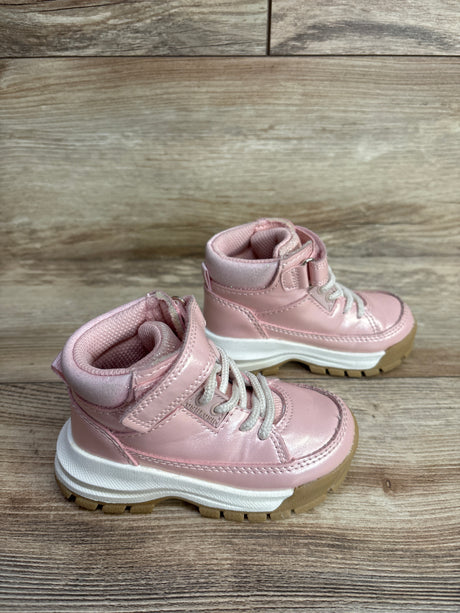 Pair of pink toddler boots with white laces and Velcro straps on wood floor background