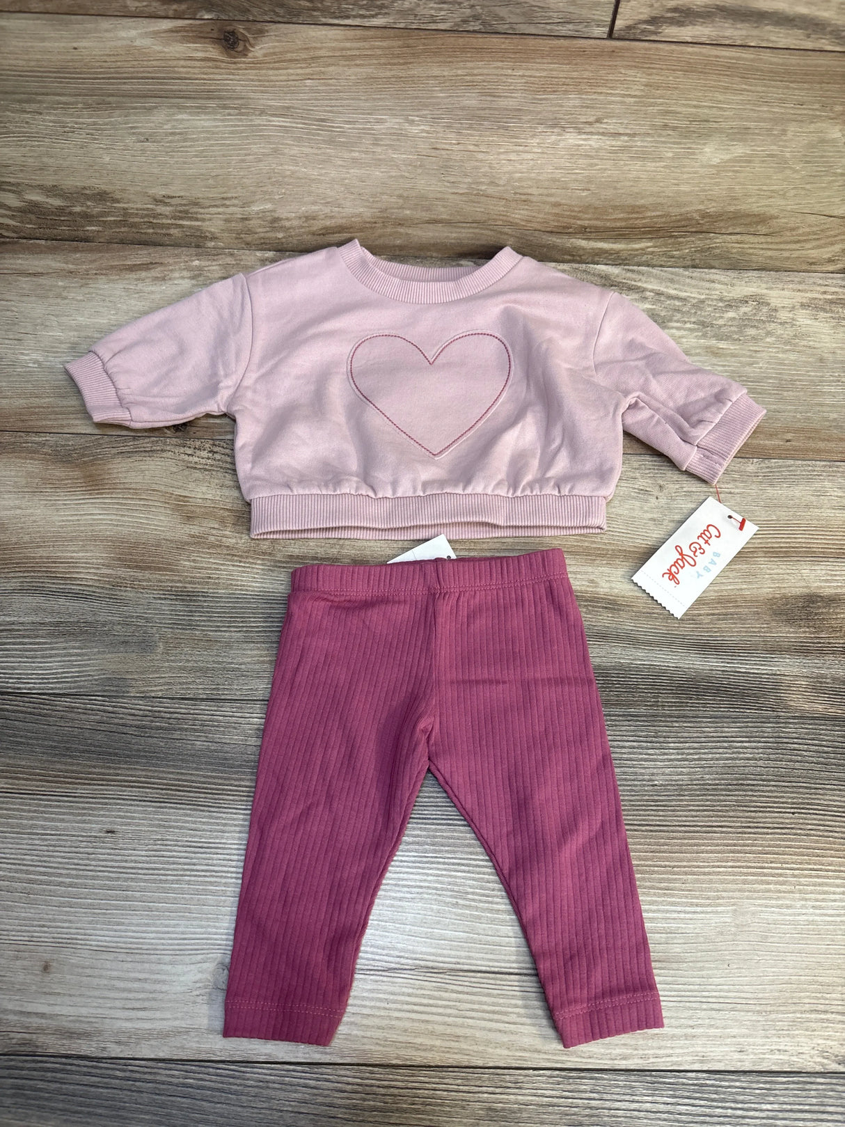 Pink toddler sweatshirt with heart design and matching ribbed leggings on wood floor