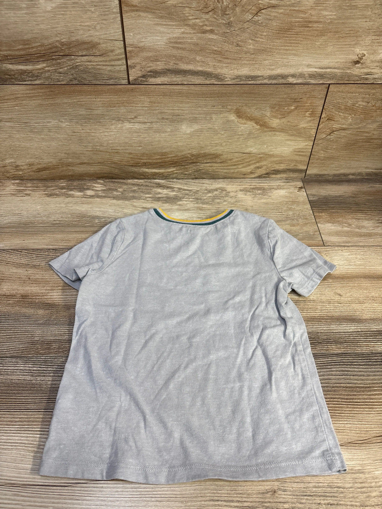 Back view of Old Navy grey heather toddler t-shirt size 5T showing green and yellow trim at the crew neckline on wood floor
