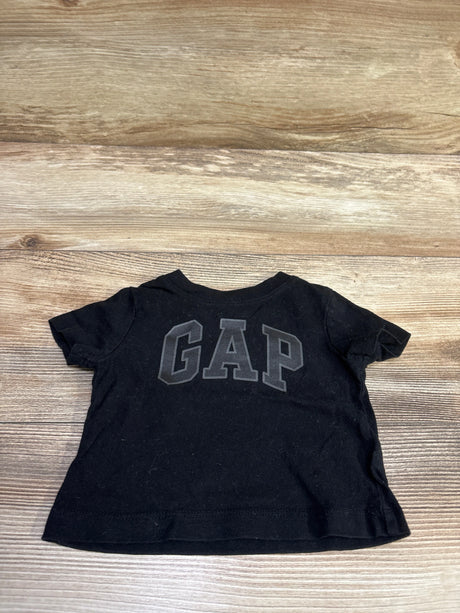 Front view of a black Baby Gap logo shirt in size 3-6 months showcasing a large GAP graphic with a wood floor background