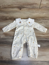 White baby romper with yellow fruit print and ruffled collar on wood floor