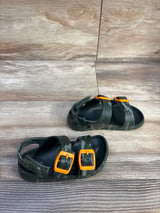 Angled top view of toddler camo Cat & Jack footbed sandals showing bright orange buckles on a wood-plank background, size 8C