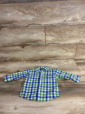 Green and blue plaid long sleeve button-up toddler shirt on wood background
