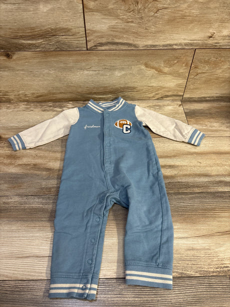 Flat-lay of Carter’s blue football snap coverall 12M with striped cuffs and embroidered football ‘C’ patch on wood background