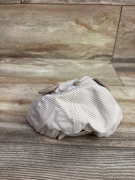 Rear view of Wander & Dreams infant bear hat in beige showcasing bear ears and striped fabric on a wood-grain floor