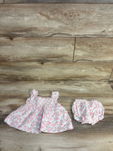 Flat lay of Janie & Jack Emily floral smocked two-piece set with ruffle straps and matching bloomers on wood background
