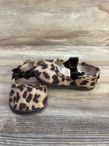 Front and side view of leopard-print baby ballet flats showcasing black velvet bows and rounded toes on a light wood surface