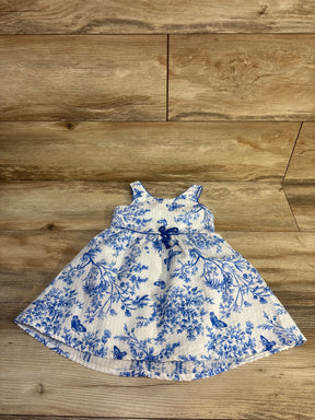 Front view of Btween white sleeveless toddler dress with blue floral print and small waist bow on wood floor