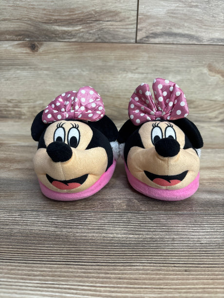 Pair of pink Minnie Mouse baby slippers with polka dot bows on wooden floor