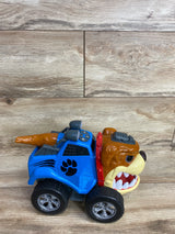 Blue toy truck with large black wheels and a brown bulldog face on front, on wooden floor