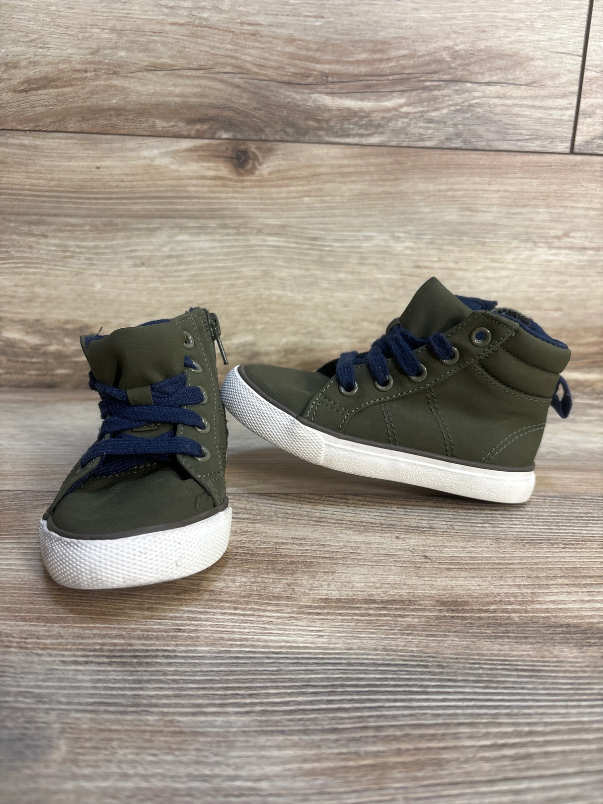 Olive green toddler high top sneakers with blue laces on wood background