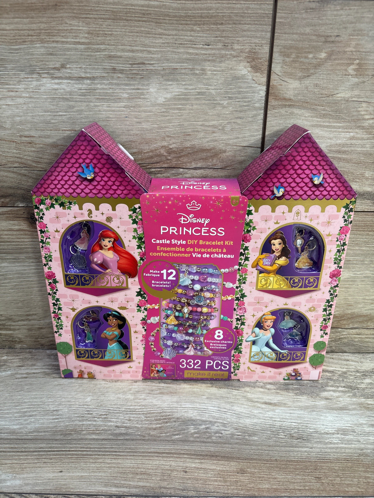 Front view of Disney Princess castle-style bracelet kit box showing 332 pieces and sample bracelets on a wooden surface