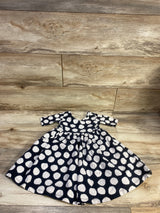 Front view of Hanna Andersson polka dot skater dress, size 3T, showcasing black fabric with white polka dots on wood floor