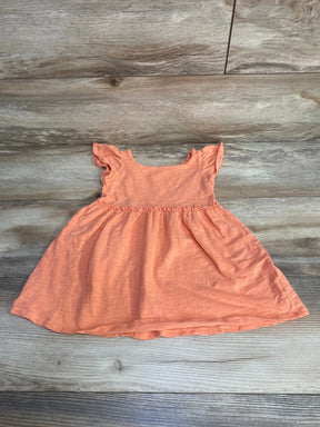 Flat lay of Cat and Jack peach baby dress, size 18 months, with flutter sleeves and gathered waist on wood background