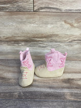 Front and side view of Stepping Stones cowgirl crib boots in pink and tan showcasing embroidered stitching and pull tabs on wood-look background