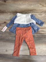 Baby outfit with blue long-sleeve dress featuring white faux fur vest and rust orange floral leggings on wooden floor