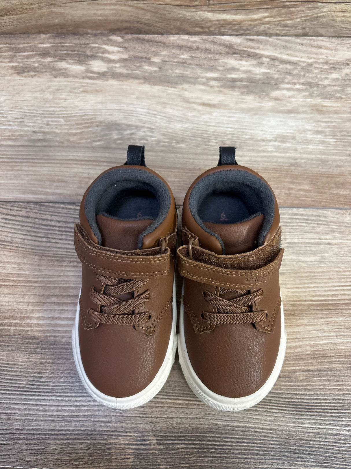 Top view of Carter's brown toddler sneakers, size 6C, showing faux-leather upper, velcro strap, and white rubber sole on wood floor