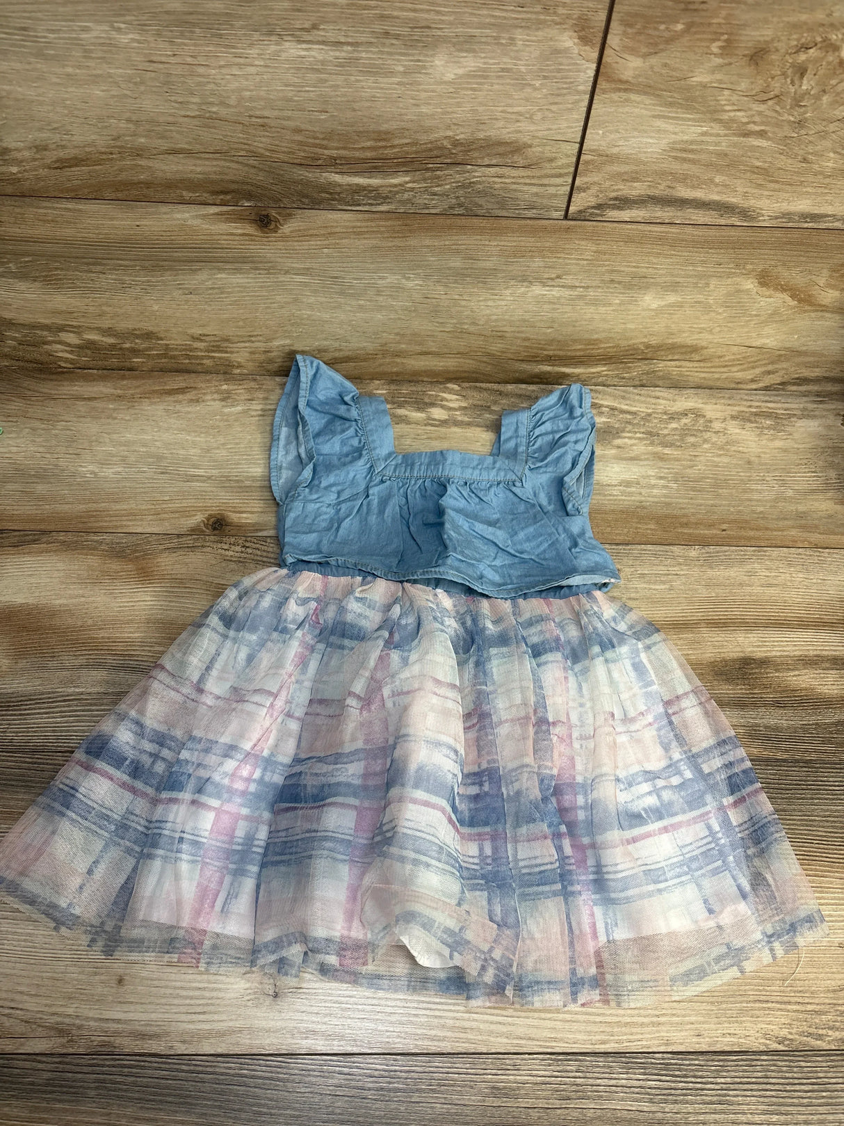 Girls' blue ruffle sleeve dress with pastel plaid tulle skirt on wood background.